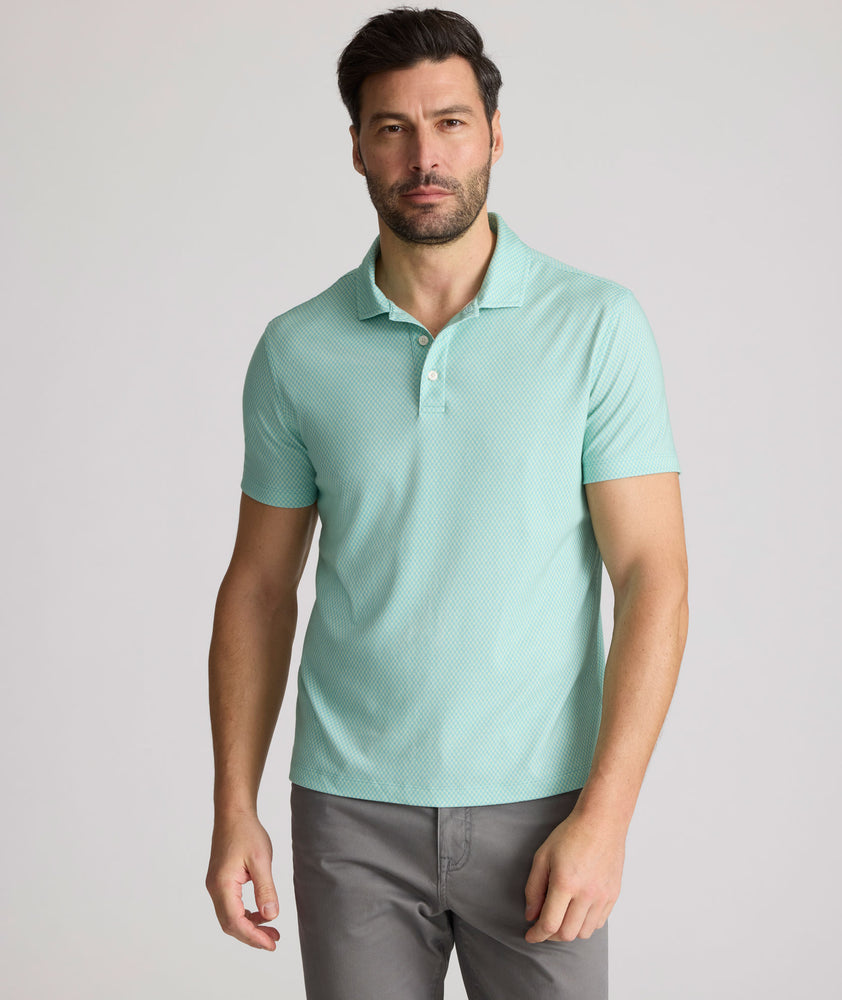 Model is wearing UNTUCKit Chen wrinkle free polo in bright green foulard print. 