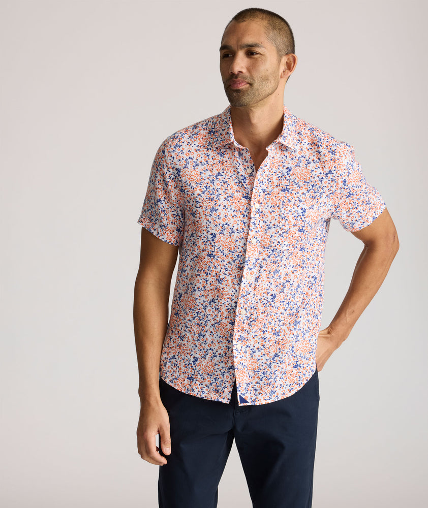 Model is wearing UNTUCKit Ellsworth Short Sleeve shirt in orange and blue floral. 