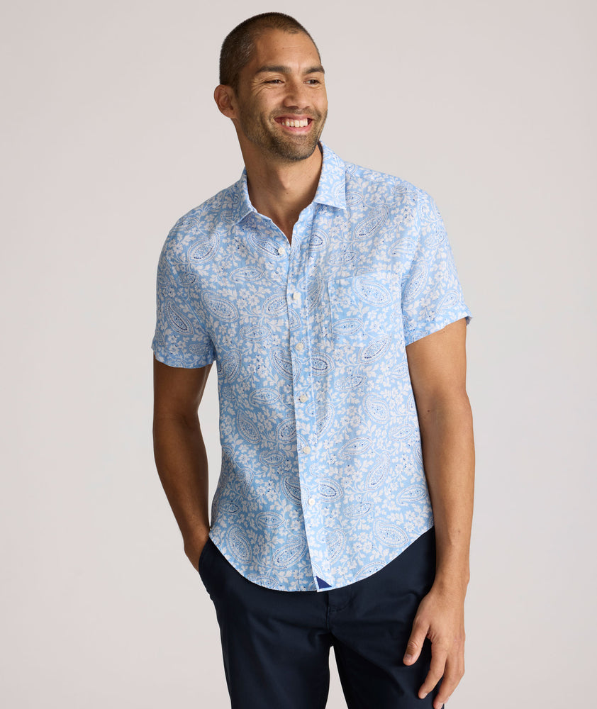 Model is wearing UNTUCKit Turner short sleeve linen shirt in light blue print. 