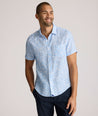 Model is wearing UNTUCKit Turner short sleeve linen shirt in light blue print. 
