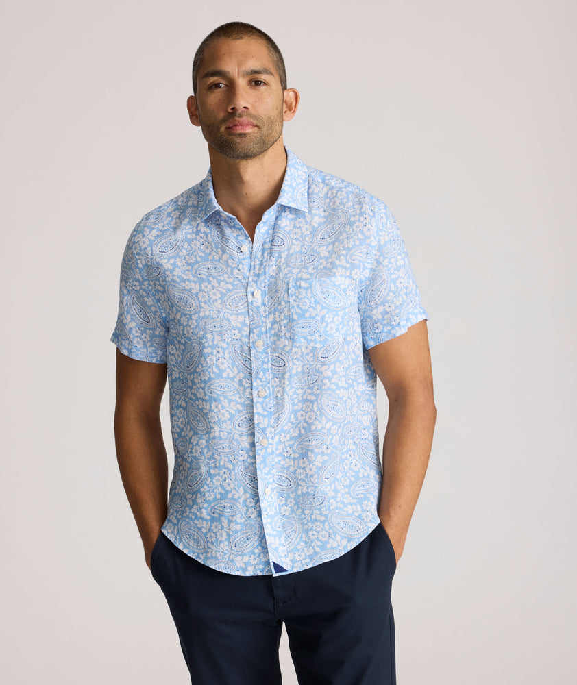 Model is wearing UNTUCKit Turner short sleeve linen shirt in light blue print. 